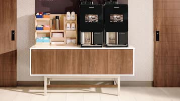 Een koffiehoek met twee koffieautomaten en een plank met koffiekopjes en een thermoskan.