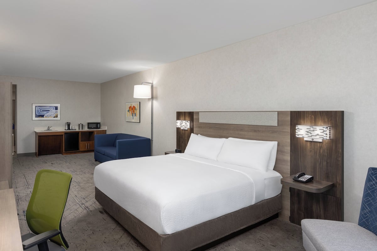 Una camera d'hotel con un letto grande, una scrivania con una sedia, un tavolino e un divano.