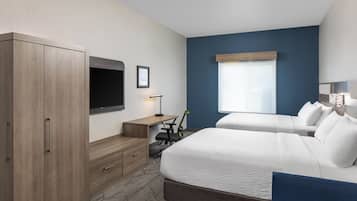 Hotelkamer met een groot bed, een bureau, een stoel, een televisie en een raam.