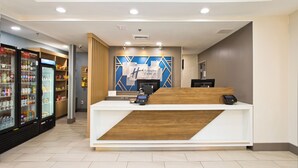 Een hotel receptie met een houten balie, een Coca-Cola koelkast en een bord met Holiday Inn Express.