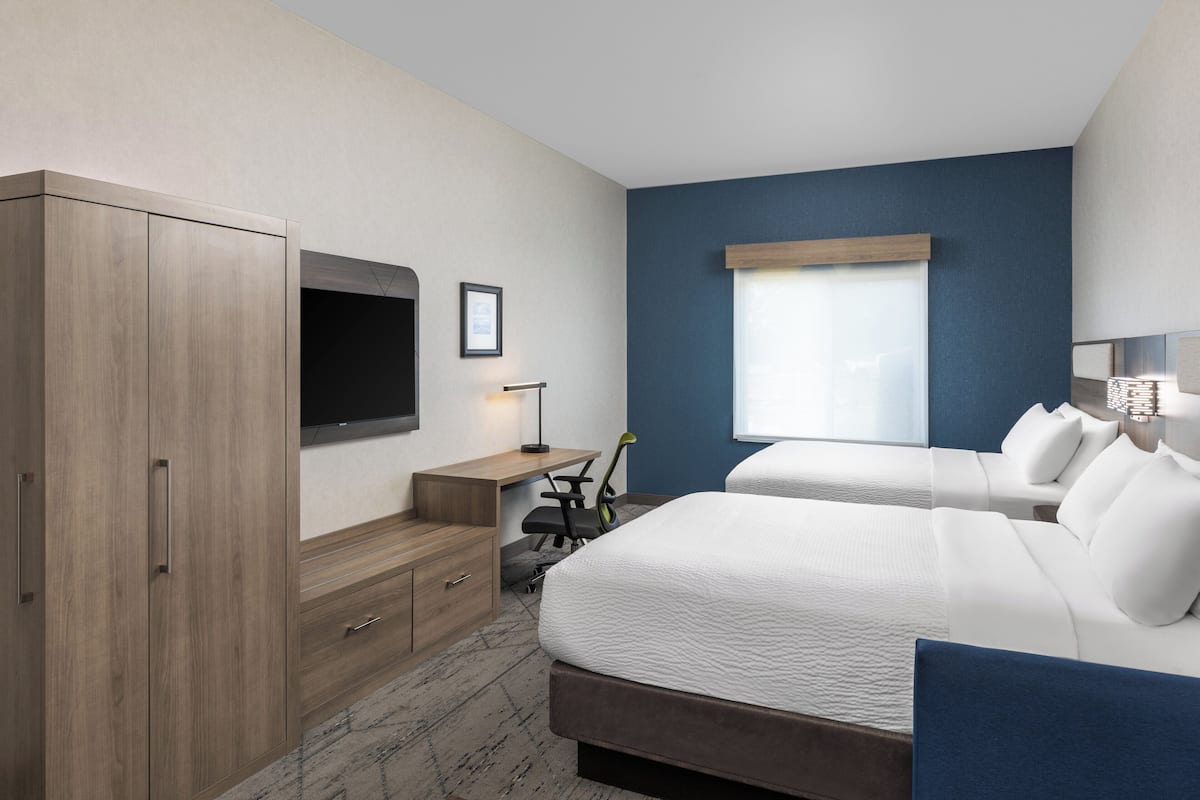 Una camera d'albergo con un letto grande, una scrivania, una sedia, una televisione e una finestra.