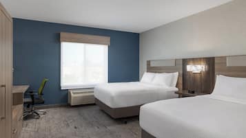 Een hotelkamer met twee bedden, een bureau, een stoel en een raam met uitzicht.