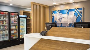 Een houten receptiebalie, een Coca-Cola koelkast en een digitaal display.