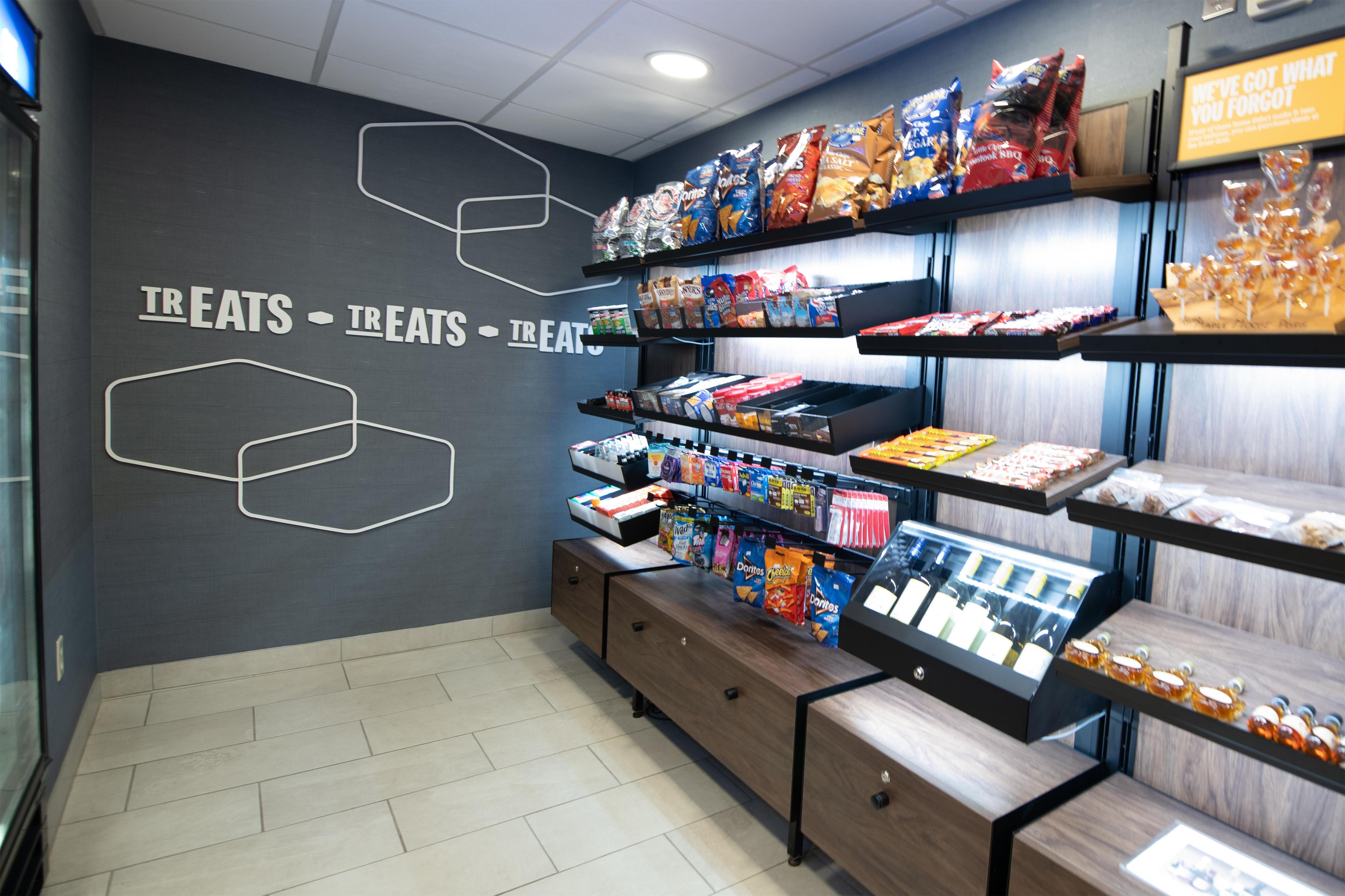 Una presentación de bocadillos con diversos productos alimenticios envasados y una pared con formas geométricas y texto.