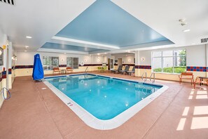 A swimming pool with a tiled deck, sun loungers, and a covered area with a blue canopy. - Hampton Inn Presque Isle Maine (Presque Isle)