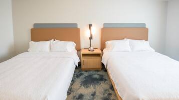 Ein Hotelzimmer mit zwei Betten, einem Nachttisch mit Lampe und einem gemusterten Teppich.