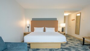 A hotel room with a bed, bedside tables, a lamp, a mirror, and a blue armchair. - Hampton Inn Presque Isle Maine (Presque Isle)