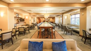 A spacious dining area with a long table and multiple seating options, including booths and chairs. - Hampton Inn Presque Isle Maine (Presque Isle)