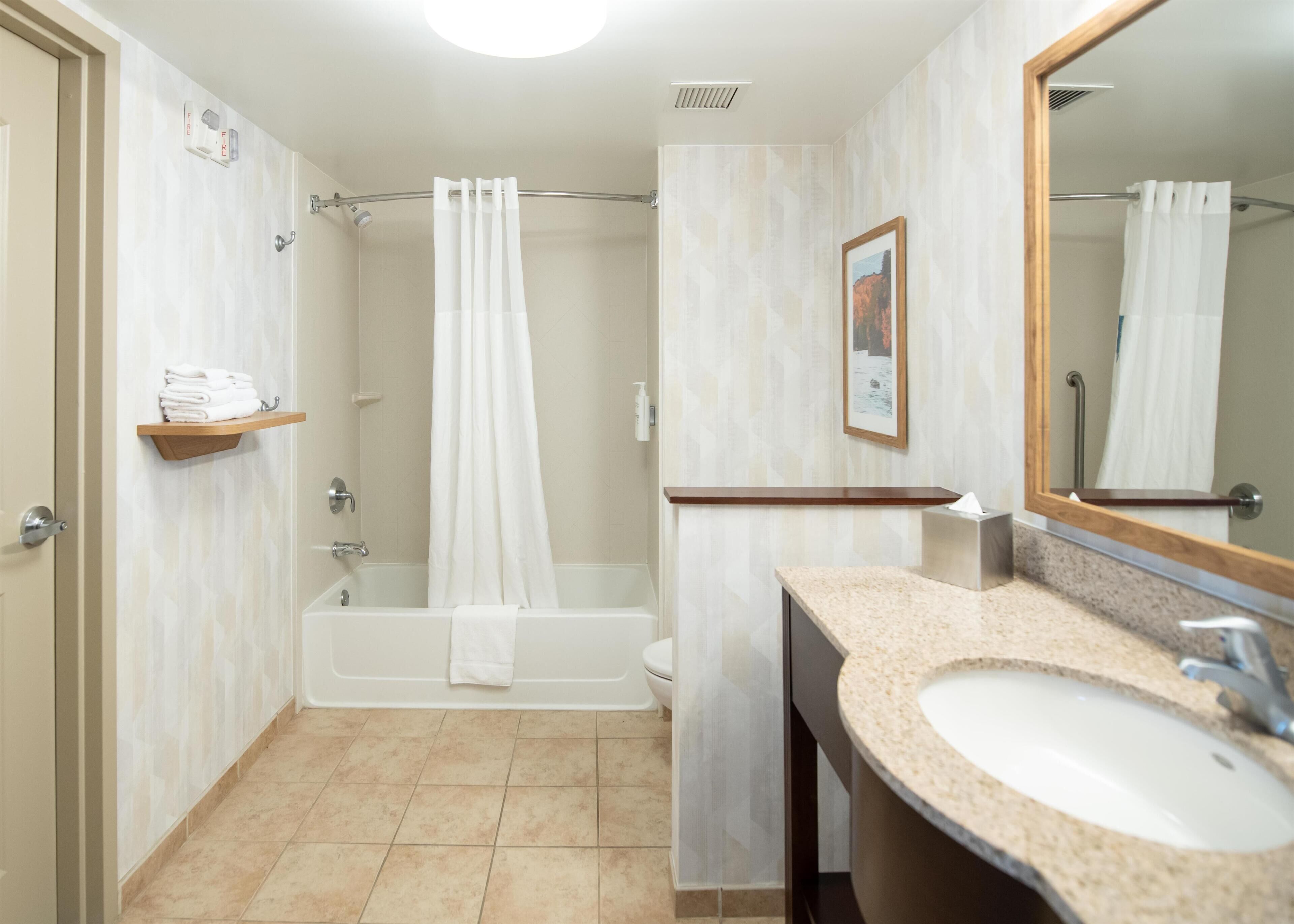 A bathroom with a bathtub, a sink, a shower curtain, and a towel rack.