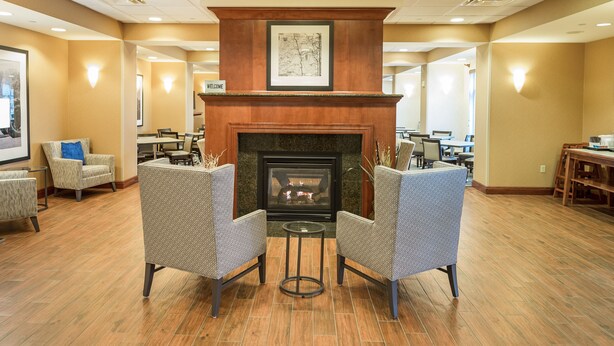 A lobby with a fireplace, seating area, and a 'Welcome' sign. - Hampton Inn Presque Isle Maine (Presque Isle)