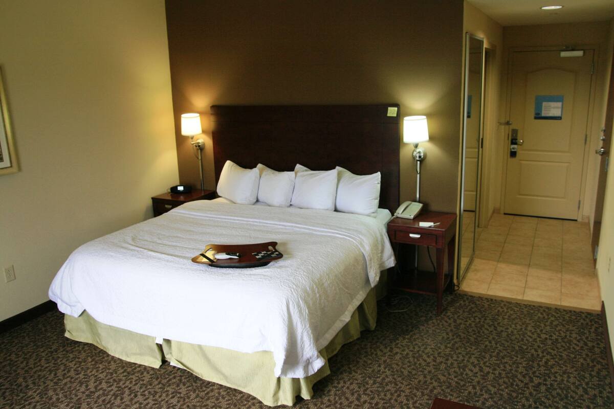 Una habitación de hotel con una cama grande, dos mesitas de noche y una puerta.