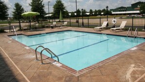 A rectangular swimming pool with a tiled deck, surrounded by a metal fence and equipped with lounge chairs and umbrellas. - Hampton Inn & Suites West Point (West Point)