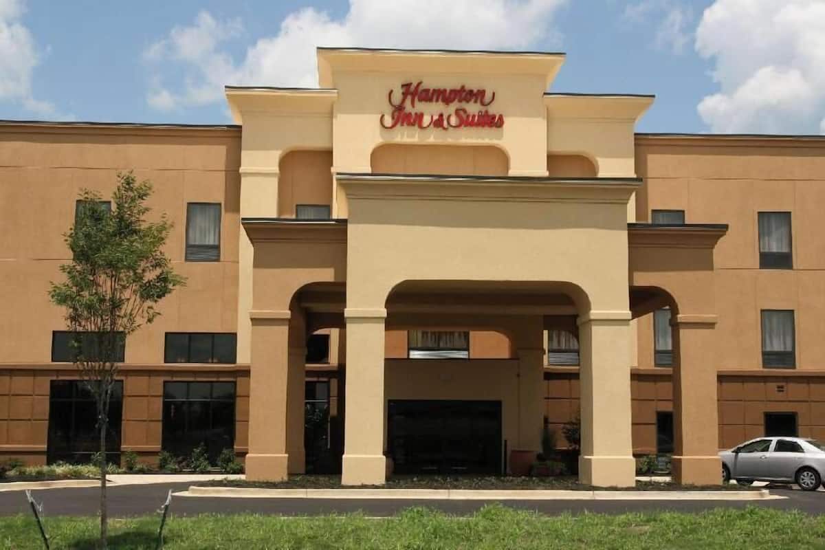 Un hotel Hampton Inn & Suites con fachada color crema, ventanas amplias y una entrada destacada.