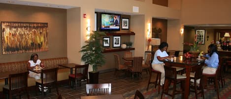 Un restaurante con una televisión sobre la barra, muebles de madera y un cuadro grande en la pared.