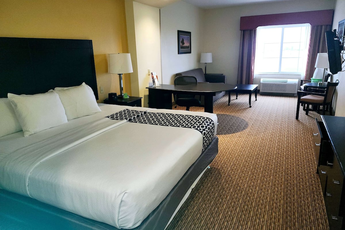 Een hotelkamer met een groot bed, een bureau, een stoel en een klein tafeltje.