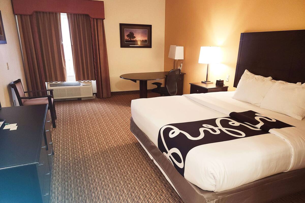 Een hotelkamer met een groot bed, een bureau, een stoel, een tafel en een lamp.