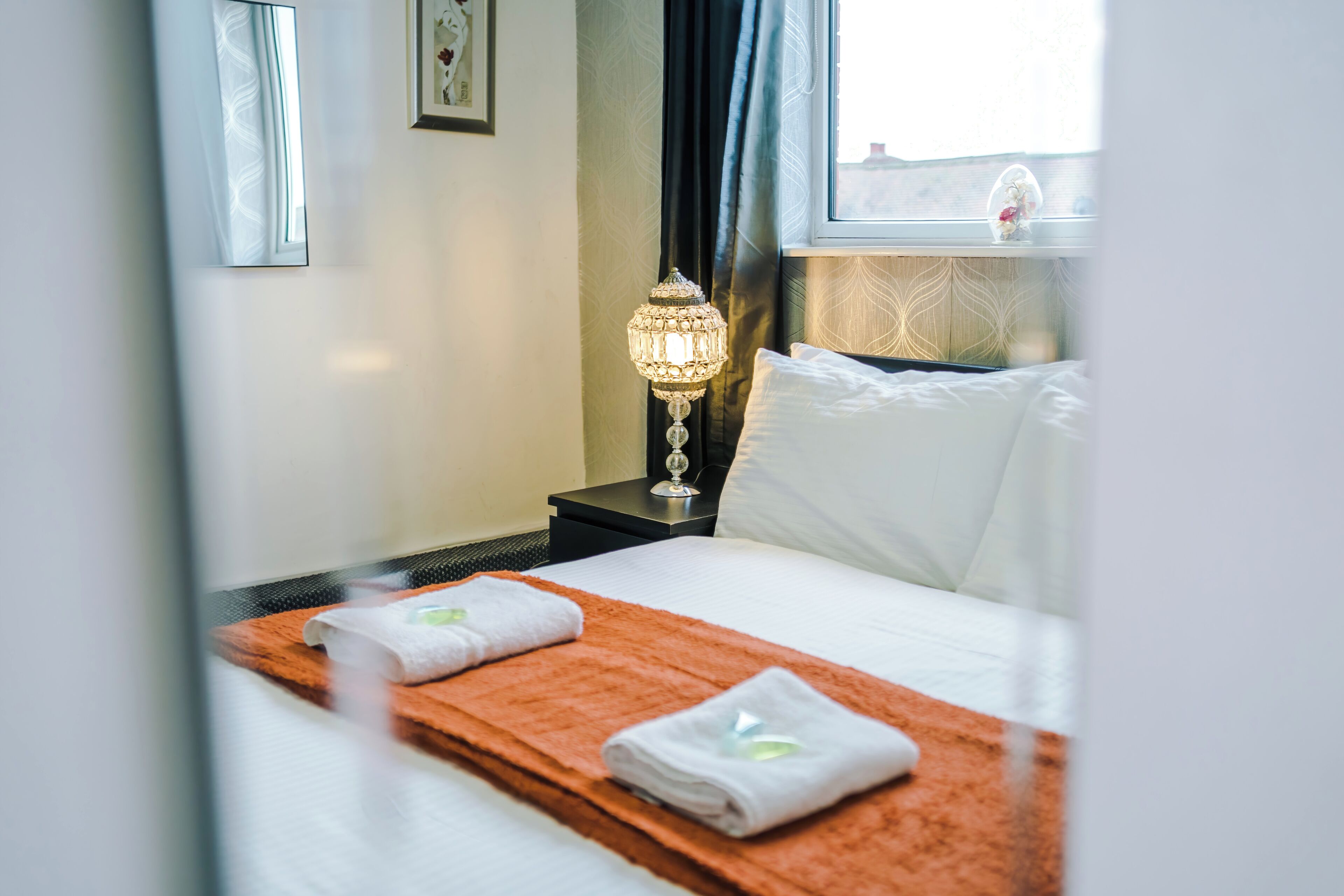 Une chambre d’hôtel avec un lit, une table de chevet, une lampe et une fenêtre.