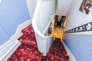 A staircase with red carpeted steps leading to a landing. - Derwent Hotel (Blackpool)