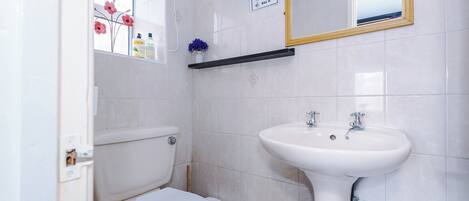 Un baño con inodoro, lavamanos y espejo.