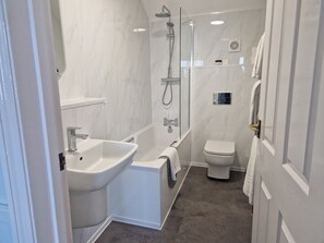 Un baño moderno con bañera, ducha, inodoro y lavamanos.