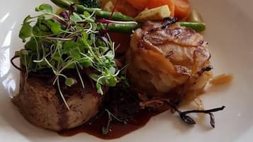 A plate of food with a piece of meat, vegetables, and a garnish.