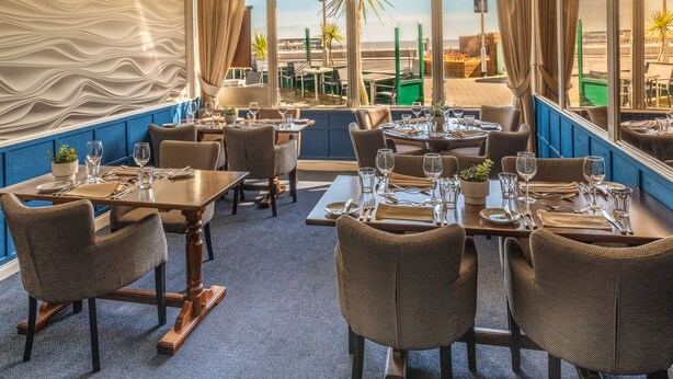 A restaurant with tables set for dining, chairs, and a view of the beach. - Dunkerleys Hotel (Deal)