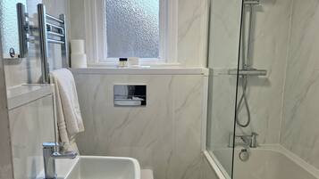 A modern bathroom with a built-in sink, toilet, and glass-enclosed shower.