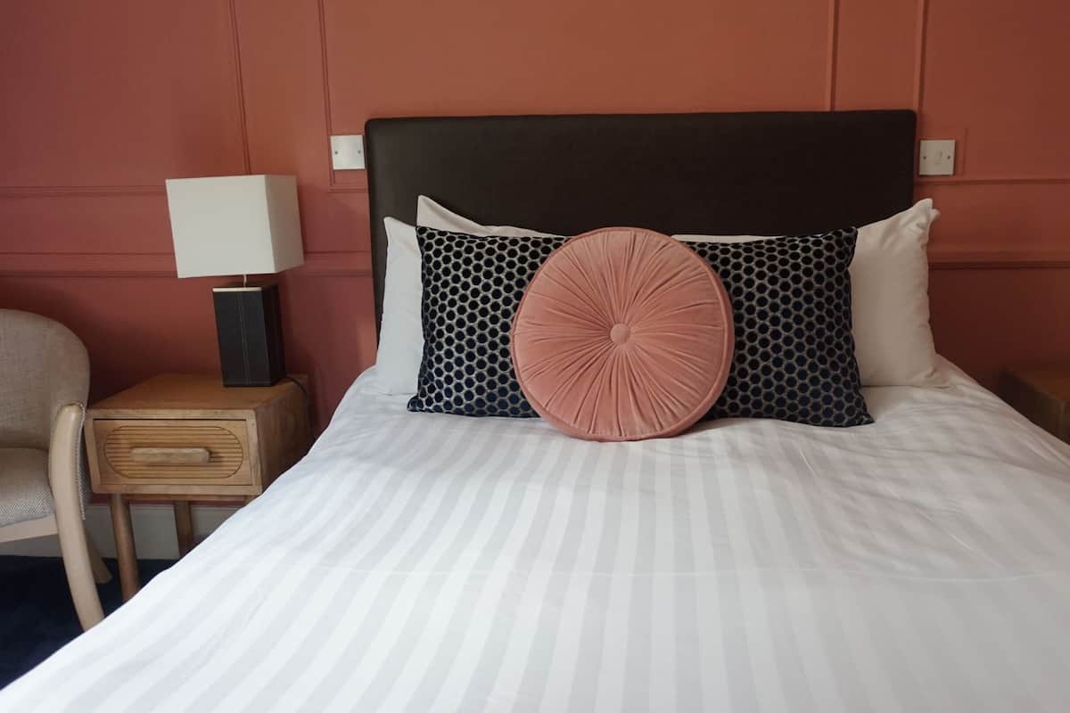A hotel room with a large bed, two bedside tables, a lamp, and a chair.