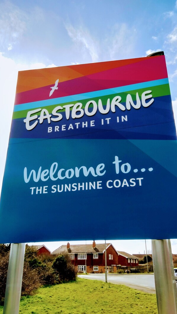 A colorful sign with 'Eastbourne' and 'Breathe it in' text, welcoming visitors to 'The Sunshine Coast'.