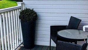 A wooden deck with a table and chairs, a potted plant, and a white railing. - Ebor Lodge (Eastbourne)