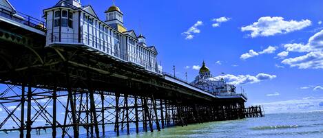 A pier with a building featuring a tower and a dome, extending into the sea.