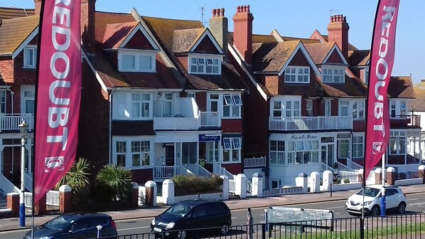A row of terraced houses with balconies, a pub named 'Ebor Lodge', and a car parked on the street.