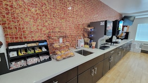 A coffee shop with a tiled backsplash, a coffee machine, and a variety of packaged goods on the counter. - Motel Capri (San Francisco)
