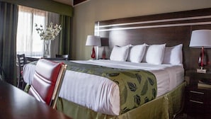 A hotel room with a large bed, two bedside lamps, a desk with a chair, and a vase with flowers. - Motel Capri (San Francisco)