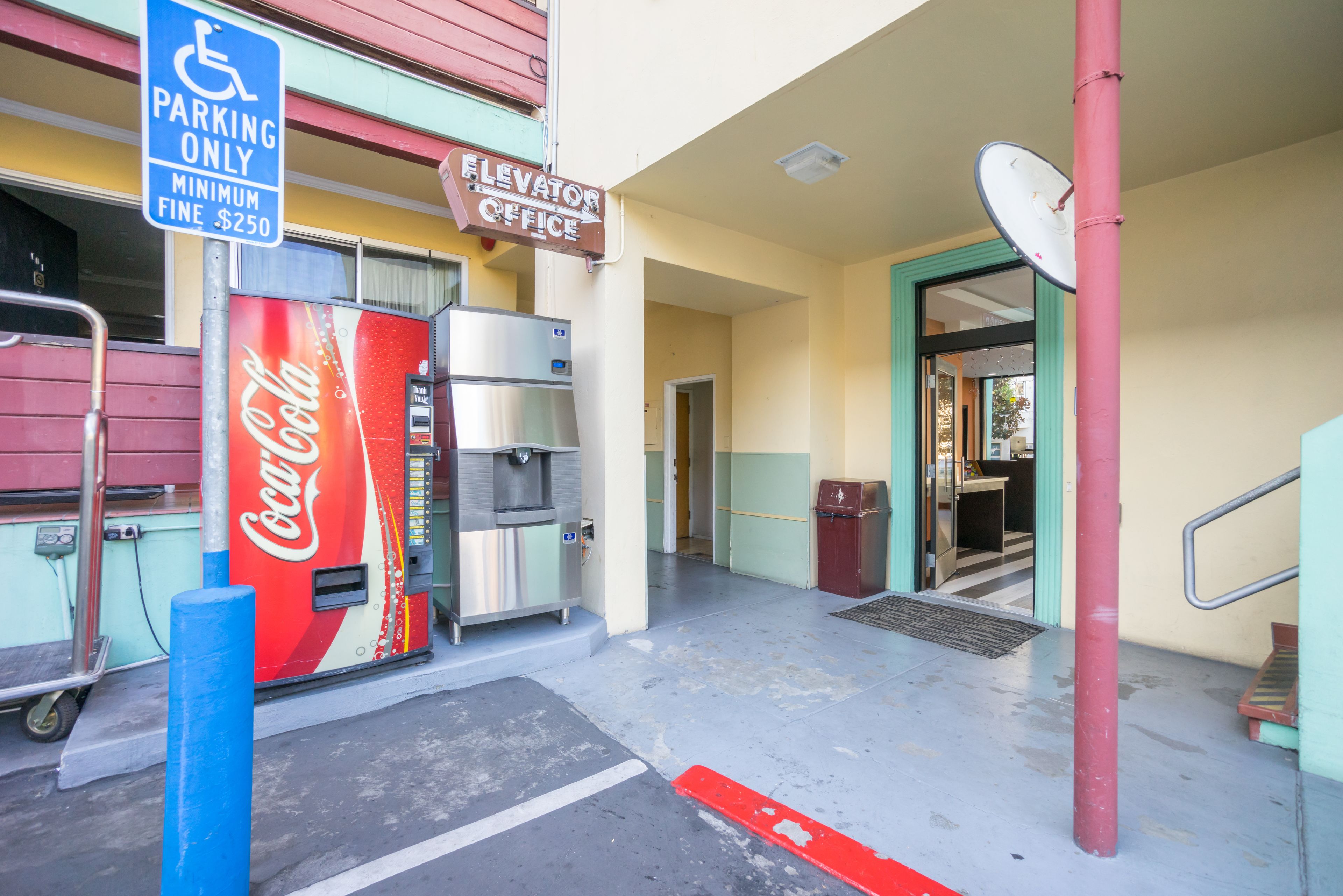 A Coca-Cola vending machine, an elevator office sign, and a disabled parking sign.