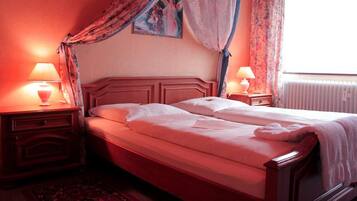 A double bed with a wooden headboard, two bedside tables with lamps, and a window with curtains.