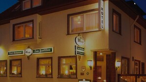 A hotel with multiple signs indicating it is a hotel and restaurant, featuring a traditional European architectural style with multiple windows and a warm, inviting entrance. - Hotel Restaurant Zum Postillion (Soltau)