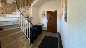 A staircase with a metal railing leading to a landing, a door, and a small round table with a vase. - Hotel Restaurant Zum Postillion (Soltau)