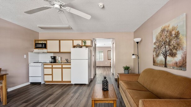 A compact living space with a kitchenette, a dining area, and a seating area with a sofa and a coffee table. - Affordable Suites Greenville (Greenville)