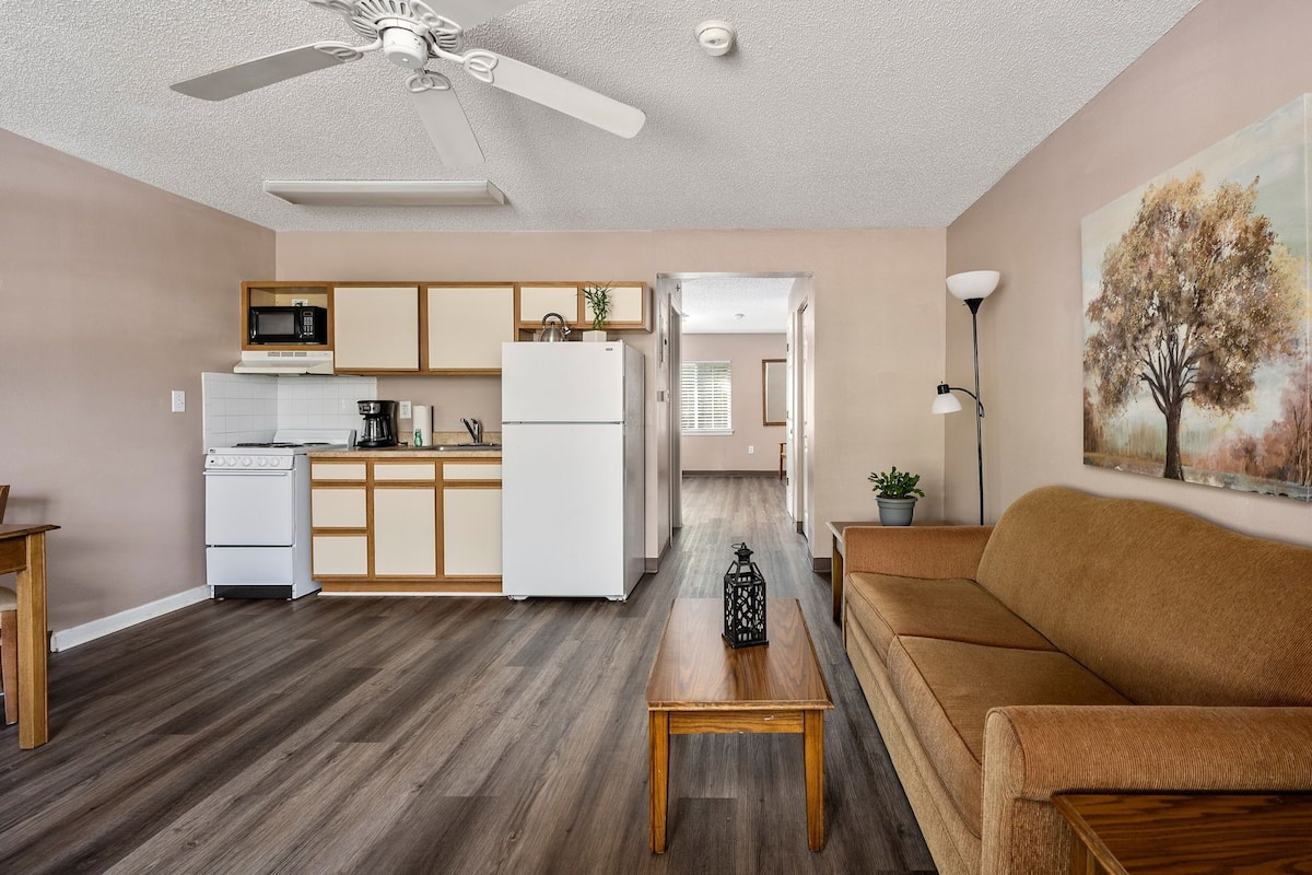 A compact living space with a kitchenette, a dining area, and a seating area with a sofa and a coffee table.