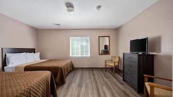 A hotel room with two beds, a dresser, a television, and a window with blinds.