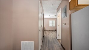 A hallway with a wooden floor, white walls, and a ceiling with recessed lighting. - Affordable Suites Greenville (Greenville)