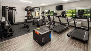 Un gimnasio con cintas de correr, elípticas y equipos de levantamiento de pesas.