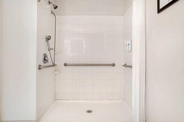 A white tiled shower with a handheld showerhead, a handheld shower head, and a grab bar. - Comfort Inn & Suites Dothan Northside Plaza (Dothan)
