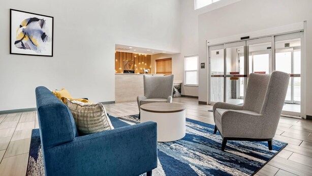 A modern hotel lobby with a blue sofa, a round coffee table, and a reception desk. - Comfort Inn & Suites Dothan Northside Plaza (Dothan)