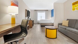 A hotel room with a desk, chair, sofa, TV, bed, and a window with curtains. - Comfort Inn & Suites Dothan Northside Plaza (Dothan)