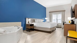 A hotel room with a large bed, a separate bathroom with a bathtub, a desk with a chair, and a TV mounted on the wall. - Comfort Inn & Suites Dothan Northside Plaza (Dothan)