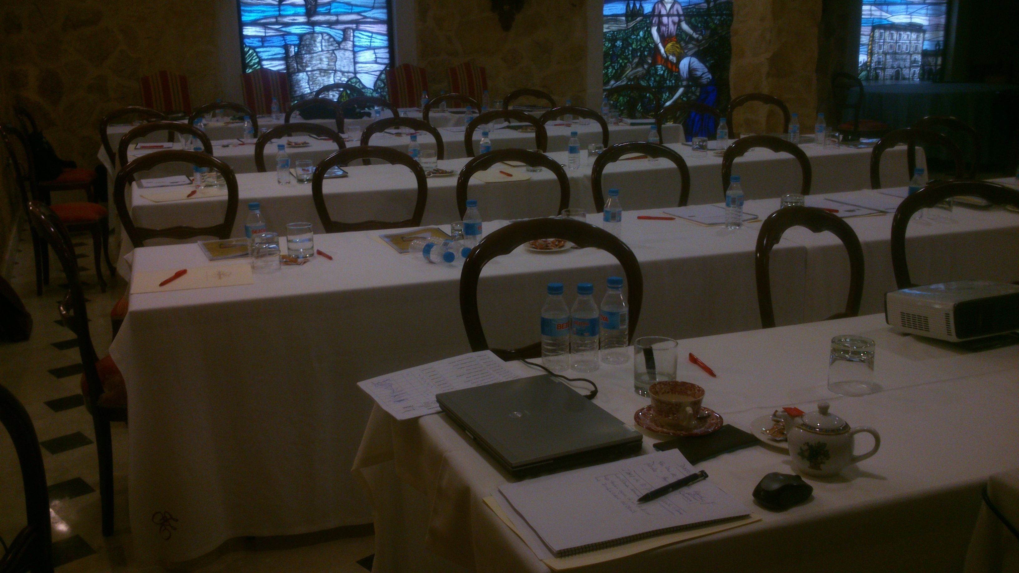 A conference room with tables set up for a meeting, equipped with laptops, notebooks, and water bottles.