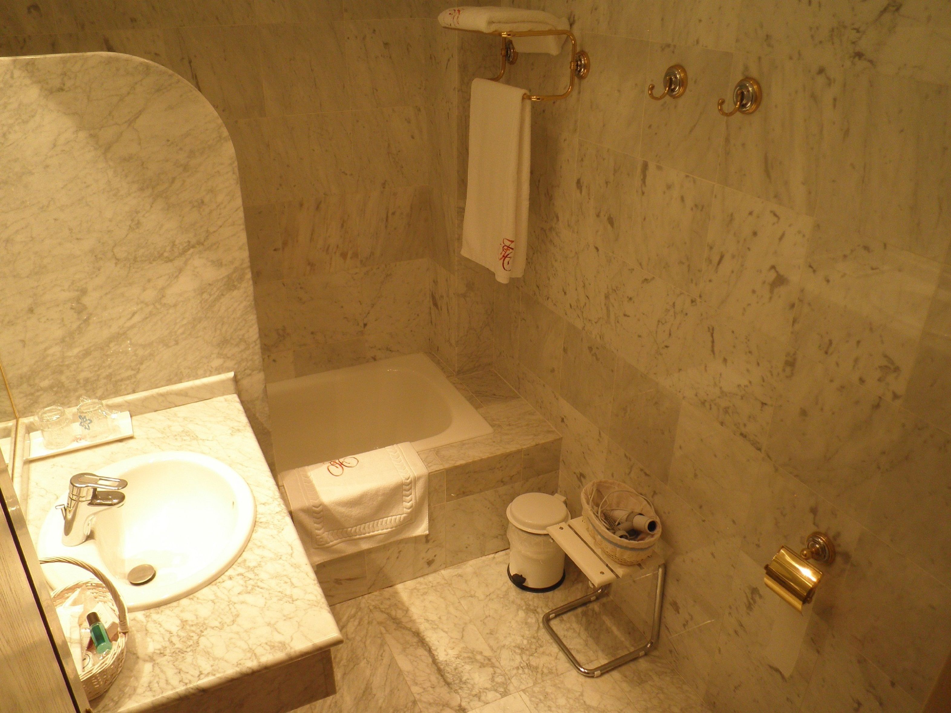 Un baño con lavamanos de mármol, bañera y retrete.