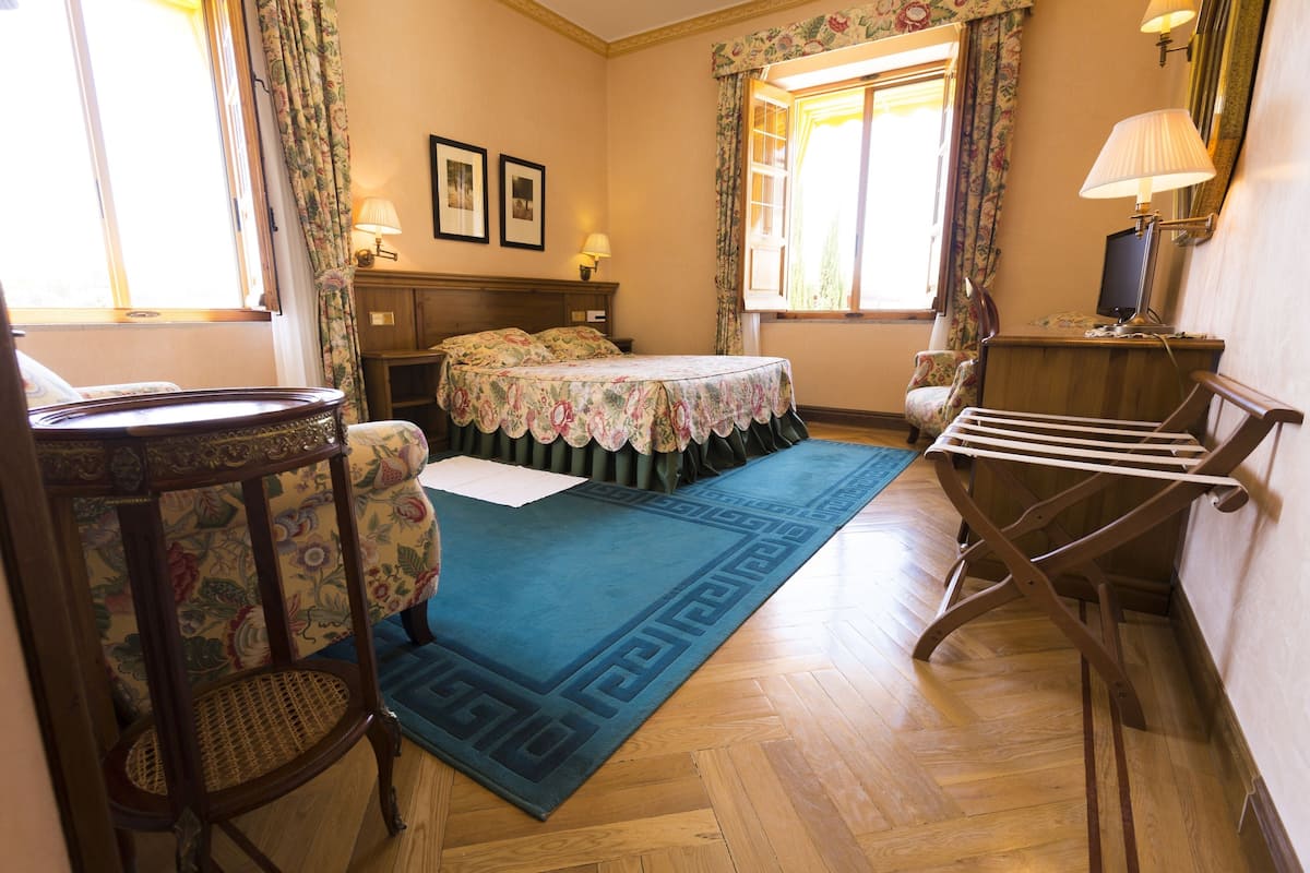 Ein Zimmer mit einem Bett, einem Sessel, einem Tisch und einer Lampe.